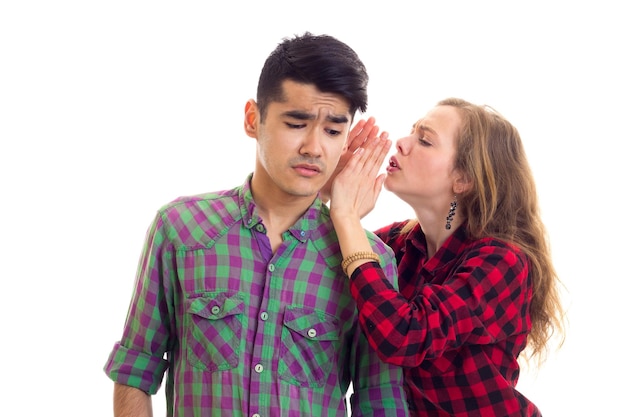 Young nice woman talking to young surprised man with dark hair in plaid shirt in studio