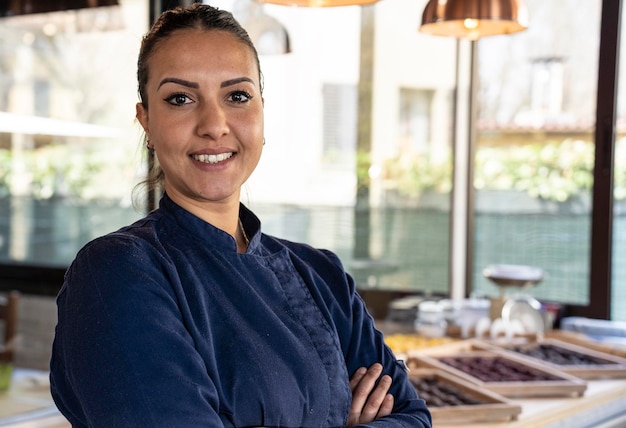 Foto giovane donna chef nordafricana sorridente sulla fotocamera al ristorante focus on face