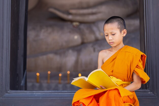 Young novice monk reading a book in Wat Phutthai Sawan Temple, Ayutthaya, Thailand