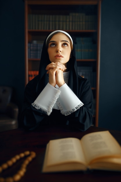 Young nun in a cassock prays crossed her arms. The sister in the monastery, religion and faith, religious people