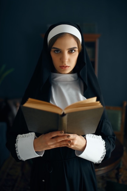 Foto giovane suora in tonaca legge una preghiera, vista frontale. la suora nel monastero, religione e fede, persone religiose