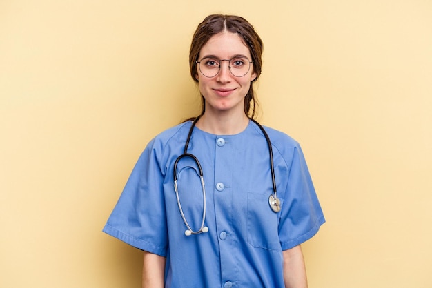 Young nurse caucasian woman isolated on yellow background happy smiling and cheerful