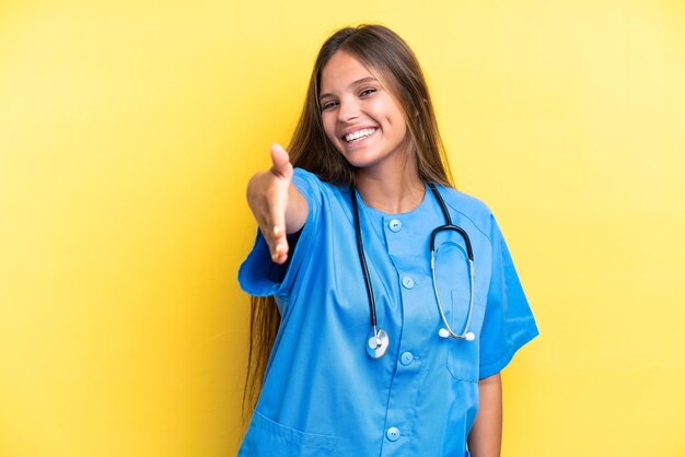 Young nurse caucasian woman isolated on yellow background shaking hands for closing a good deal