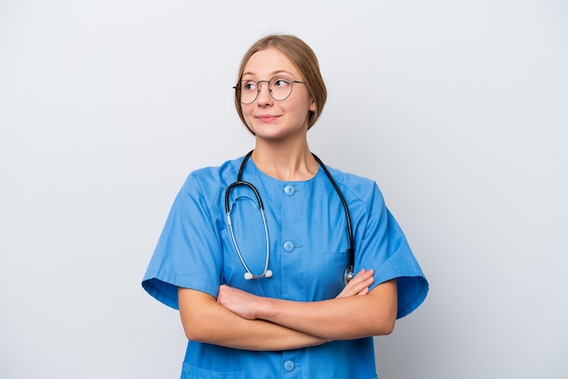 Молодая медсестра-врач женщина изолирована на белом фоне, делая жест сомнений, поднимая плечи