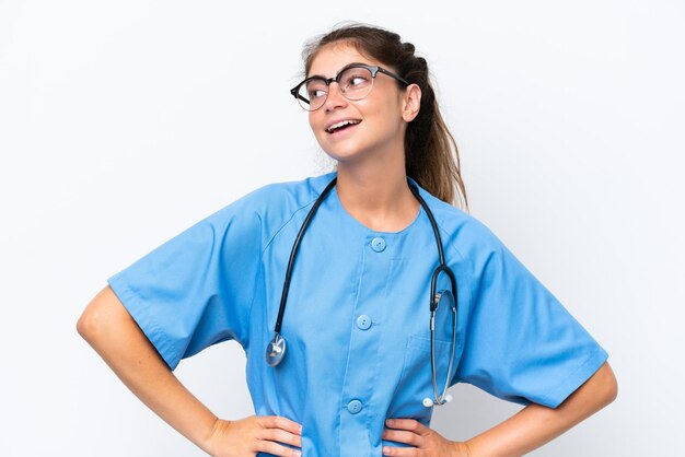 Молодая медсестра-доктор изолирована на белом фоне, позирует с руками на бедрах и улыбается