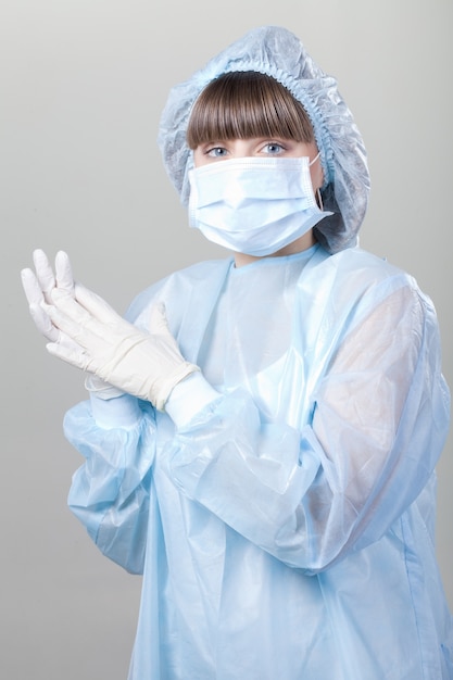 Фото Молодая медсестра в медицинских перчатках и больничной маске на белом