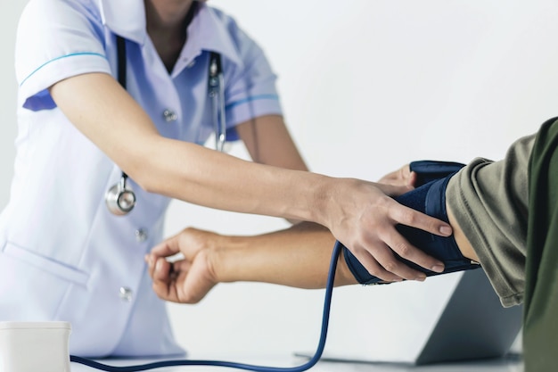 A young nurse is measuring the pressure of a patient who is admitted to the hospital.