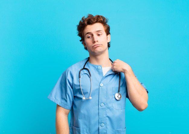 若い看護師の男性は、ストレス、不安、疲れ、欲求不満を感じ、シャツの首を引っ張って、問題で欲求不満に見える