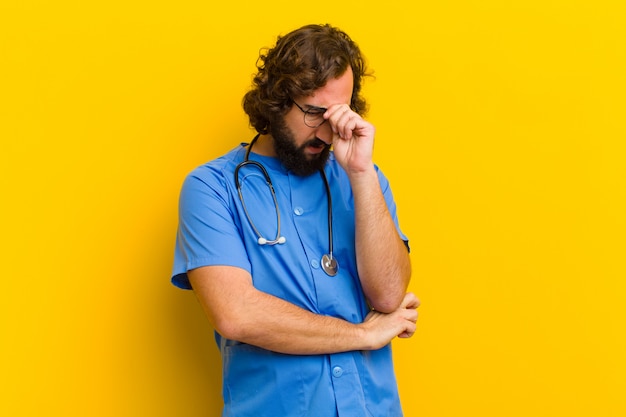 Young nurse man thinking against yellow wall