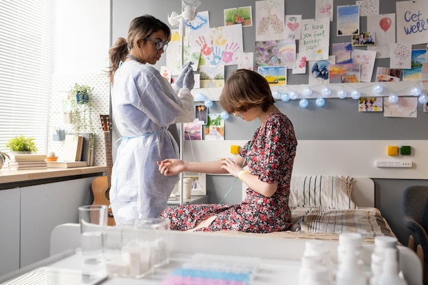 Young nurse standing by dropper while looking at teenage patient