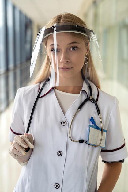 Young nurse stands in the hallway and holds a stethoscope