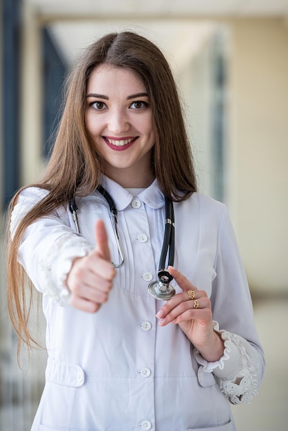 A young nurse stands with a stethoscope and holds medical magazines and books in her hands