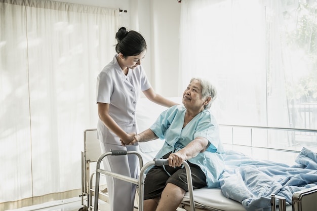 若い看護師は病院の部屋で高齢者の世話をする