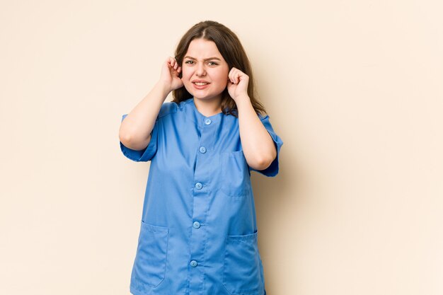 Young nurse woman covering ears with hands.