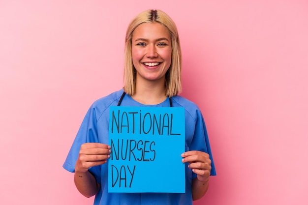 Young nurse woman holding a international nurses woman banner isolated on pink wall