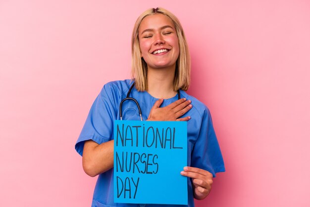 Photo young nurse woman holding a international nurses woman banner isolated on pink wall