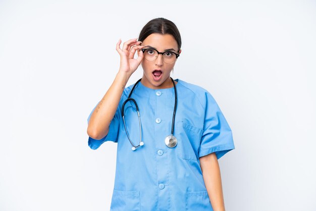 Young nurse woman isolated on white background with glasses and surprised