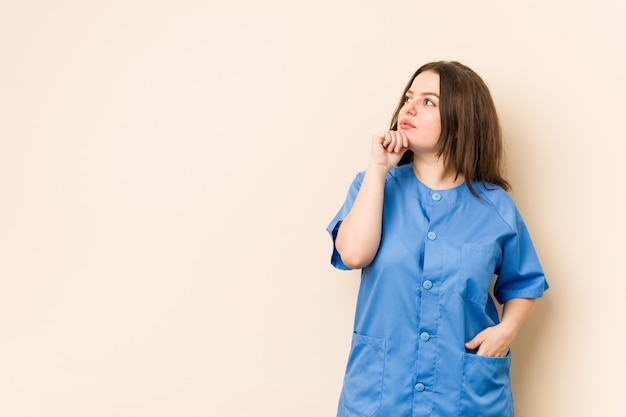 Young  nurse woman looking sideways with doubtful and skeptical expression.