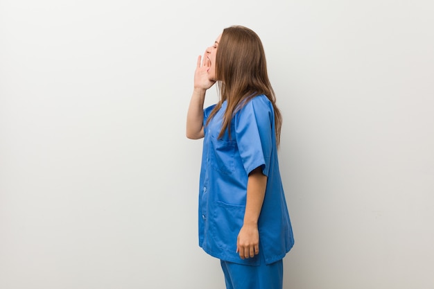 Молодая медсестра кричит и держит ладонь возле раскрытого рта