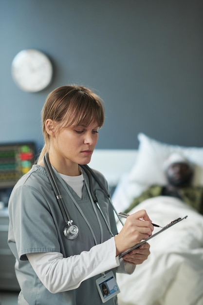 Young nurse writing down medical prescriptions for patient