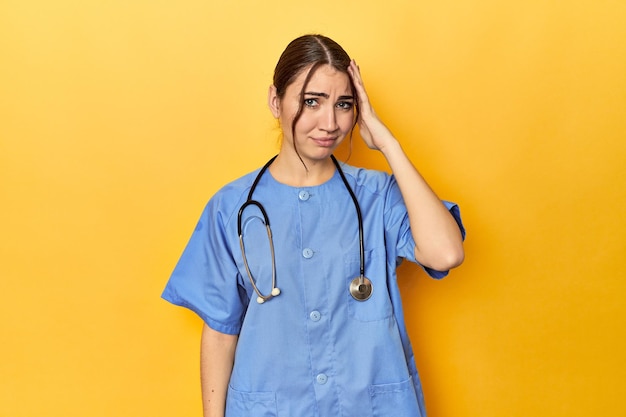 Photo young nurse in a yellow studio being shocked she has remembered important meeting