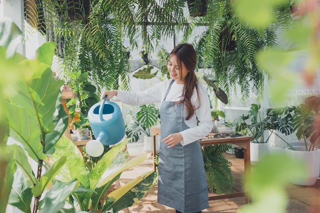 Photo young nursery worker in greenhouse.  home gardening, love of plants and care. small business.