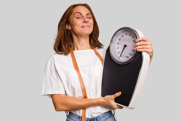 Young nutritionist caucasian woman holding scale and mesure tape isolated