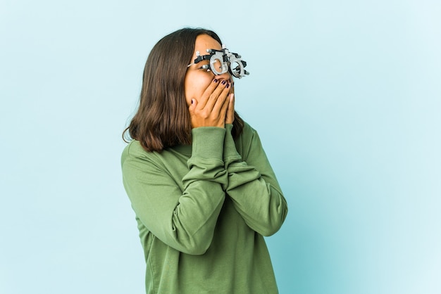 Young oculist latin woman laughing about something, covering mouth with hands.