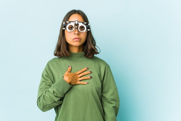 Young oculist latin woman taking an oath, putting hand on chest.