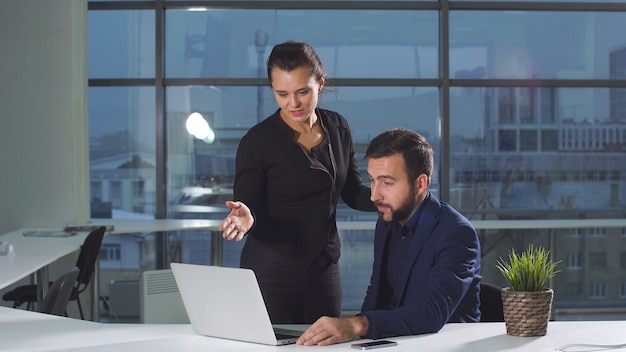 Young office colleagues are working on a computer while discussing online project