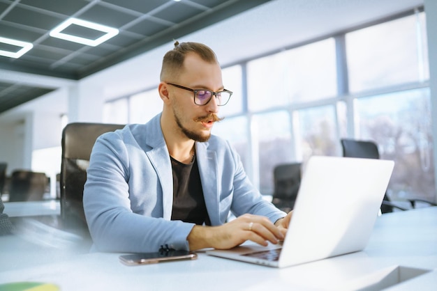 Young office manager working with papers and computer working at office Businessman writes reviews