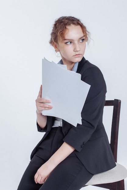 Young office worker girl in classic suit keeps clean sheets of paper on white. 