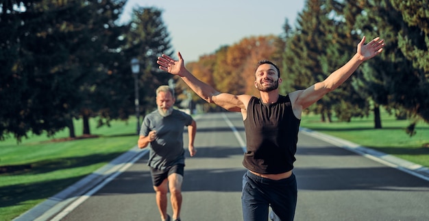 The young and old sportsmen running on the road