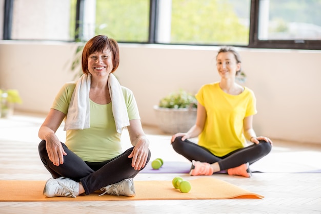 Young and older woman in sports wear sitting during the yoga training indoors