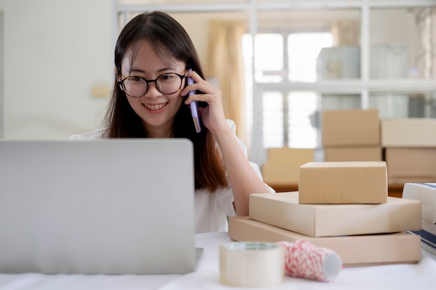 Young online seller talking on phone to receive and checking order from customers