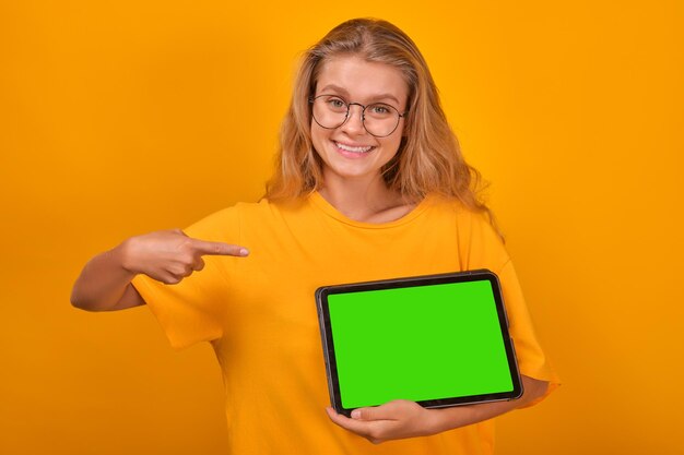 Young optimistic caucasian woman schoolgirl demonstrates green tablet computer