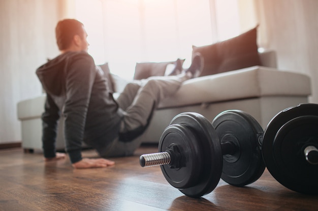 Foto giovane uomo ordinario che fa sport a casa. taglia la vista di un principiante o di una matricola in attività di allenamento nel suo appartamento.