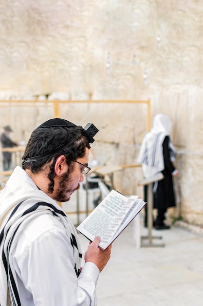 Young Orthodox Jewish man praying with phylacteries tefilin at the Western Wall