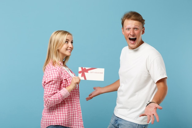 Young overjoyed couple two friends guy and woman in white pink empty blank t-shirts posing 