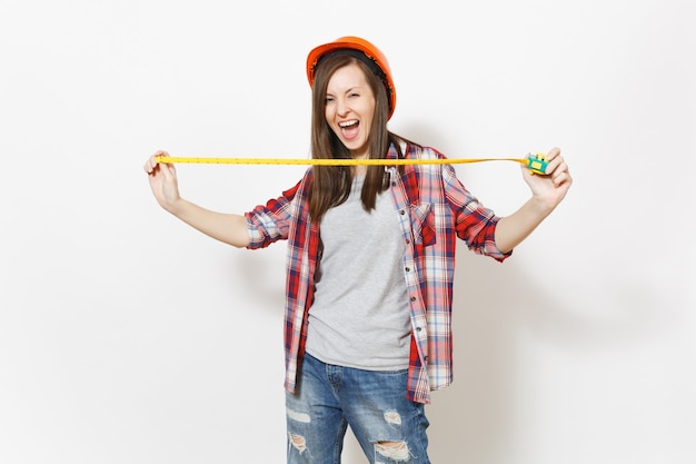 Young overjoyed woman in casual clothes, protective construction helmet holding toy measure tape isolated on white background. Instruments, tools for renovation apartment room. Repair home concept.