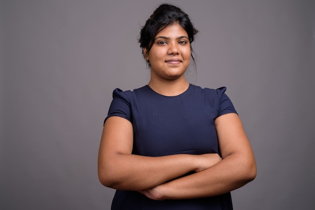  young overweight beautiful Asian woman against gray wall