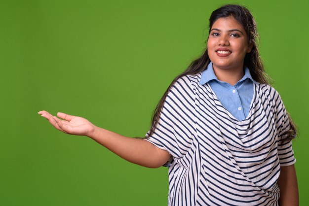 Photo young overweight beautiful indian businesswoman against green wall