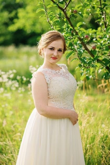 Giovane ragazza in sovrappeso in abito beige poste sullo sfondo del giardino di primavera