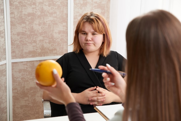 Young overweight woman visiting nutritionist to lose weight with help of diet