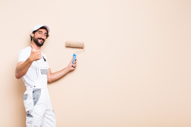 Young painter bearded man celebrating his success and holding a roller paint