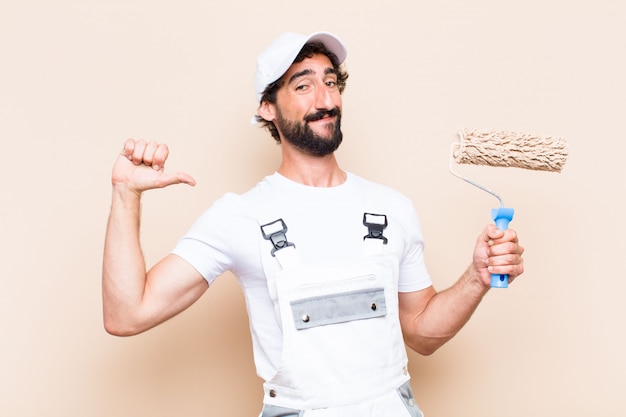 Young painter bearded man holding a roller and proud expression