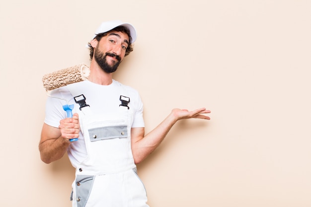 Young painter bearded man holding a roller an showing something