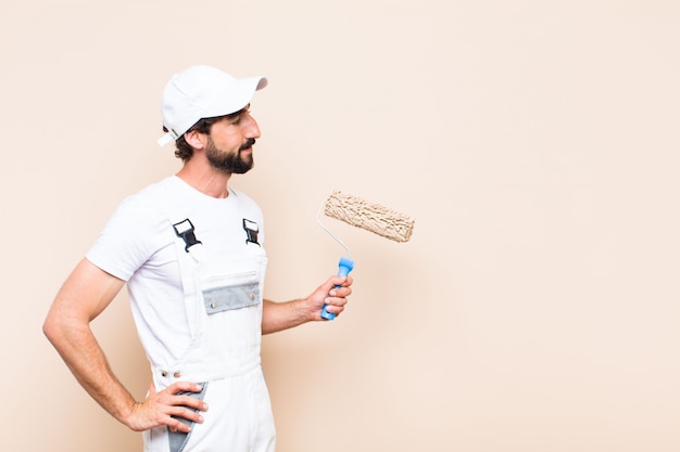 Young painter bearded man painting a wall with a paint roller