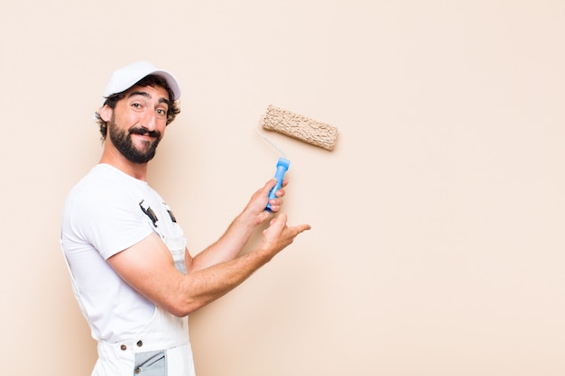 Young painter bearded man painting a wall with a paint roller