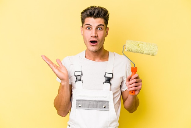 Young painter man isolated on yellow background surprised and shocked.